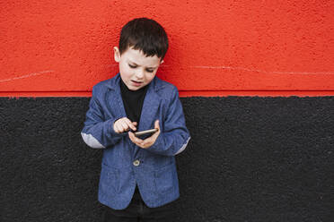 Porträt eines kleinen Jungen im Anzug mit Smartphone - LJF01312