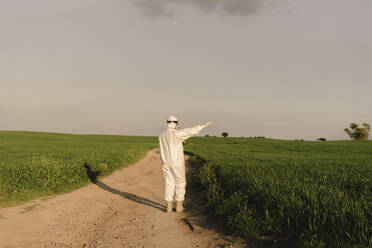Man wearing protective suit and mask in the countryside - ERRF02629