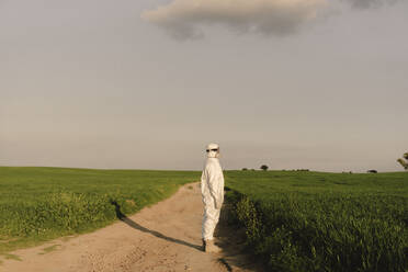 Man wearing protective suit and mask in the countryside - ERRF02630