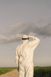 Rear view of man wearing protective suit in the countryside - ERRF02633