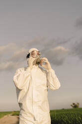 Man wearing protective suit and mask in the countryside - ERRF02635