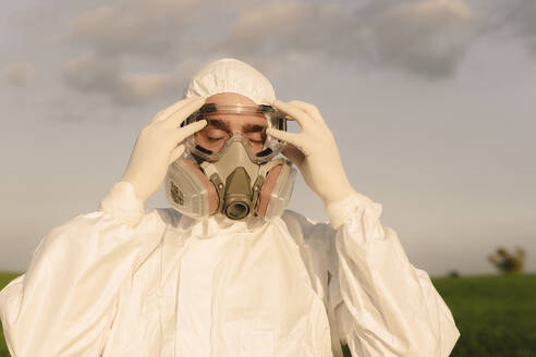 Portait of man with closed eyes wearing protective suit and mask - ERRF02636
