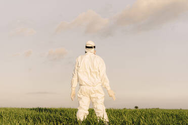 Rear view of man wearing protective suit in the countryside - ERRF02651
