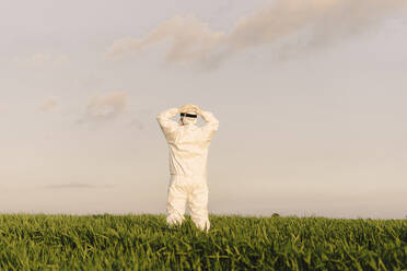 Rear view of man wearing protective suit in the countryside - ERRF02652