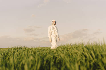 Mann mit Schutzanzug und Maske in einem Feld - ERRF02653