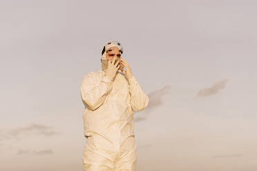Man wearing protective suit and mask in the countryside - ERRF02667