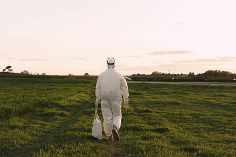 Rückansicht eines Mannes mit Schutzanzug bei einem Spaziergang in der Natur, lizenzfreies Stockfoto