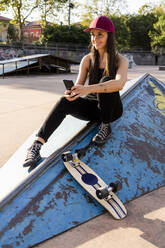 Junge Frau mit Smartphone und Skateboard im Skatepark - GIOF08008