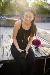 Young laughing woman with smartphone at skatepark - GIOF08016