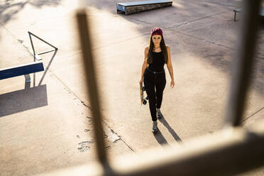 Junge Frau mit Skateboard im Skatepark - GIOF08019