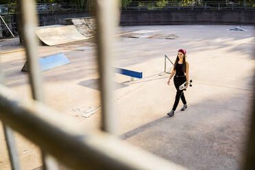 Junge Frau mit Skateboard im Skatepark - GIOF08021