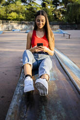 Young woman using smartphone at skatepark - GIOF08028