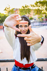 Junge Frau formt Rahmen mit ihrem Finger im Skatepark - GIOF08037