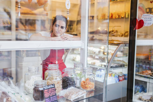 Junge Frau arbeitet in einer Bäckerei und schaut aus dem Fenster - LJF01342