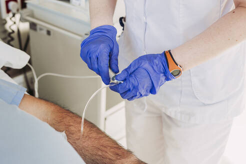 Nurse adjusting iv drip for patient lying in hospital bed - LJF01355