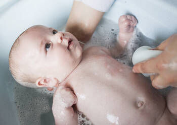 Mutter badet ihren kleinen Jungen in einer Wanne - LJF01359