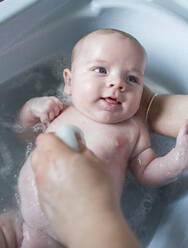 Mother bathing her baby boy in a tub - LJF01361