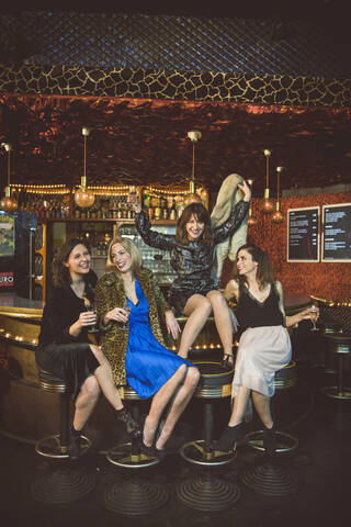 Vier glückliche Frauen sitzen an der Bar in einem Club, lizenzfreies Stockfoto