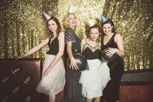 Porträt von vier glücklichen Frauen mit Partyhüten in einem Club - HBIF00048