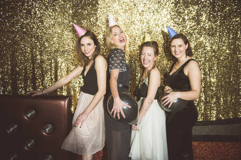 Porträt von vier glücklichen Frauen mit Partyhüten in einem Club - HBIF00049