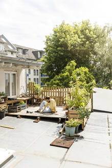 Junger Mann baut Terrasse auf dem Dach - PESF01795