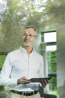 Senior Mann mit grauen Haaren in modernem Design Wohnzimmer hält Tablet - SBOF02098