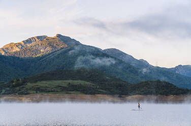 Man stand up paddle surfing on a lake in the fog - DGOF00457