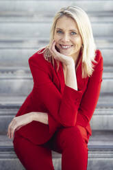 Blonde lächelnde Geschäftsfrau im roten Anzug, die in die Kamera schaut - JSMF01444
