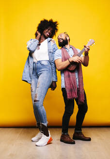 Happy young man with woman in studio playing ukulele - DGOF00472