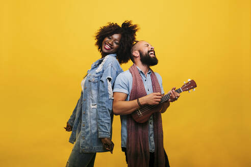 Happy young man with woman in studio playing ukulele - DGOF00474