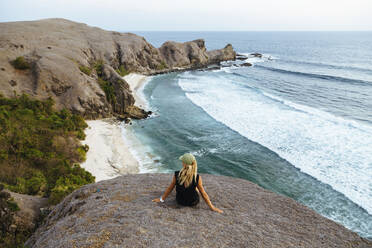 Young woman sitting on rock at sunset - CAVF75439