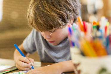 Six year old boy drawing amoung colorful pens - MINF13822