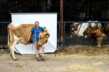 Porträt einer Bäuerin vor einer Scheune mit einer Guernsey-Kuh. - MINF14002