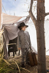 Six year old boy playing in an outdoor tent made of sheets - MINF14029