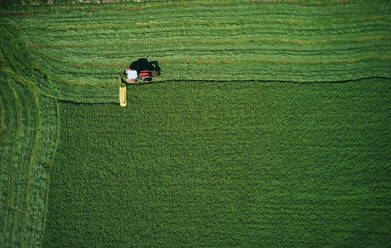 Tractor working on green field furrowing wheat - CAVF75491