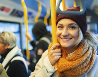 Porträt selbstbewusste junge Frau mit Strumpfmütze und Schal im Bus - HOXF05033