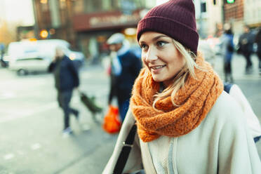 Junge Frau mit Strumpfmütze und Schal auf einer städtischen Straße - HOXF05050