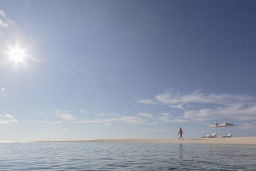 Mann, der an einem sonnigen, ruhigen, abgelegenen Strand spazieren geht, Malediven - HOXF05062