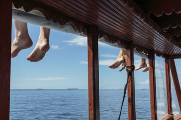 Nackte Füße baumeln über dem sonnigen Ozeandock, Malediven - HOXF05063