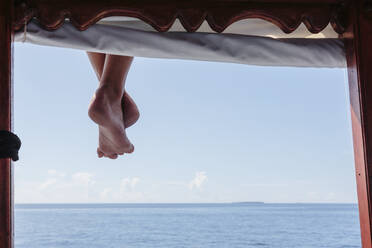 Nackte Füße hängen vom Steg über dem sonnigen Ozean, Malediven - HOXF05077