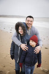 Portrait happy family with Down Syndrome child on beach - HOXF05088