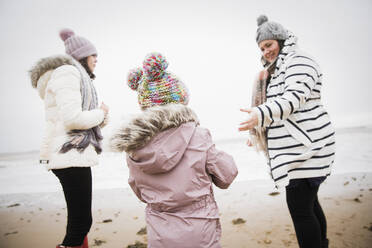 Familie in warmer Kleidung am winterlichen Meeresstrand - HOXF05090