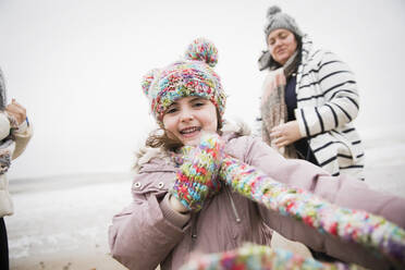 Porträt glückliches sorgloses Mädchen in warmer Kleidung am Winterstrand - HOXF05095