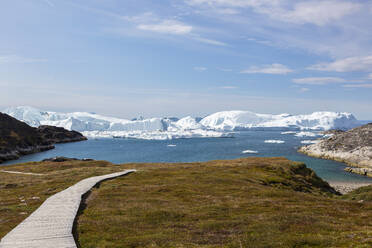 Sonniger Fußweg zum Strand mit Blick auf Eisberge in Grönland - HOXF05109