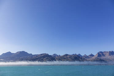 Blauer Himmel über majestätischer Berglandschaft und Meer Grönland - HOXF05114