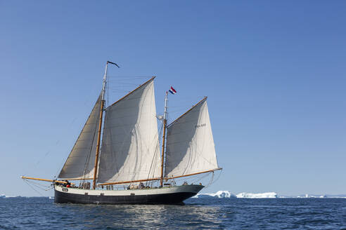 Schiff mit niederländischer Flagge über dem sonnigen Atlantik in Grönland - HOXF05139