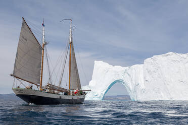 Schiff fährt durch Eisberg Bogen auf sonnigen blauen Atlantik Grönland - HOXF05143