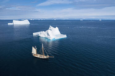 Schiff fährt an majestätischen Eisbergen auf dem sonnigen blauen Atlantik vorbei Grönland - HOXF05179