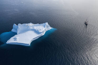 Schiff fährt an majestätischer Eisbergformation auf blauem Atlantik vorbei Grönland - HOXF05180