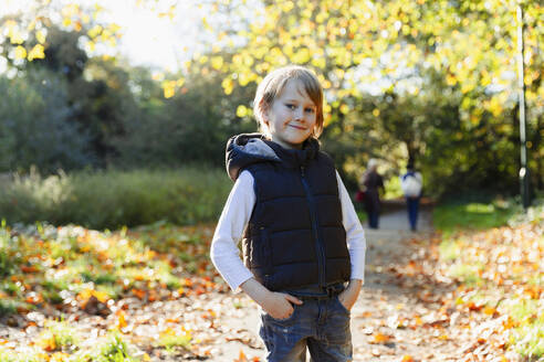 Portrait selbstbewusster Junge im sonnigen Herbstpark - HOXF05191
